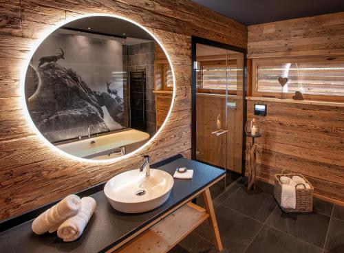 a bathroom with a sink and a round mirror at Chalets Alpglück in Oberstdorf