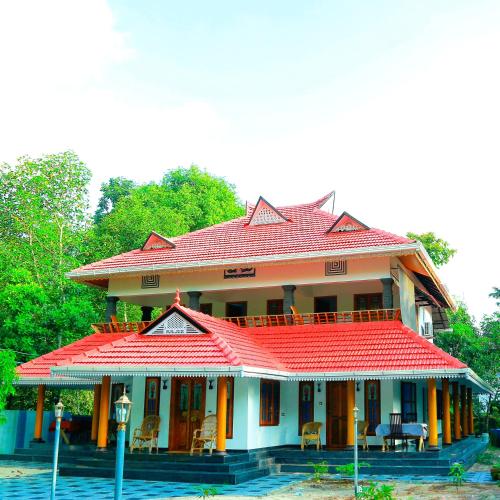 a house with a red roof with chairs in front of it at Telma Beach Homestay in Mararikulam