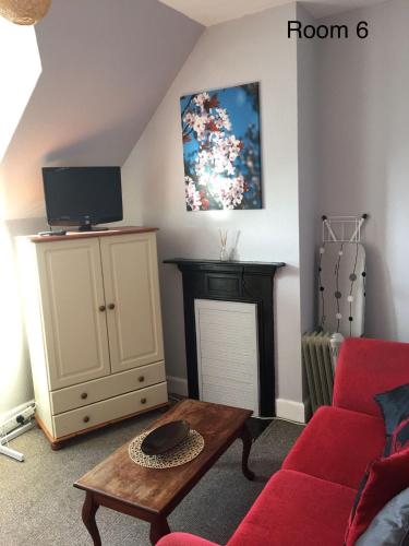 a living room with a red couch and a tv at The Royal Oak in Weymouth