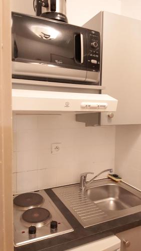 une cuisine avec un évier et un micro-ondes dans l'établissement studio, à Tignes