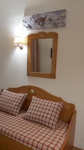 - un lit avec 2 oreillers et un miroir mural dans l'établissement studio, à Tignes