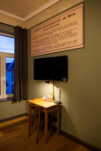 a room with a table and a television on a wall at Storyhotel Bergischer Hof Königswinter in Königswinter