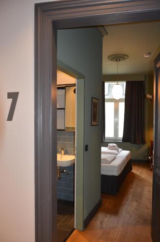 a bedroom with a bed and a bathroom with a sink at Storyhotel Bergischer Hof Königswinter in Königswinter