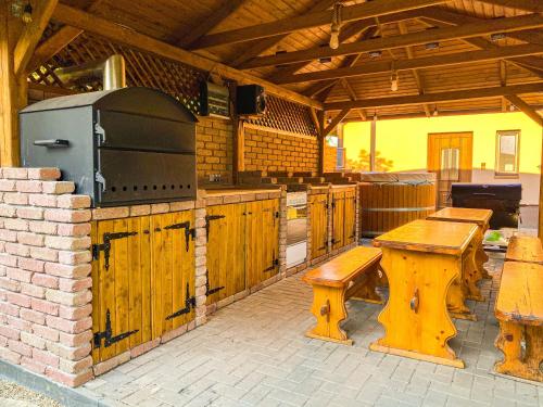 an outdoor kitchen with wooden benches and a grill at Bárdos Vendégház in Tiszabábolna
