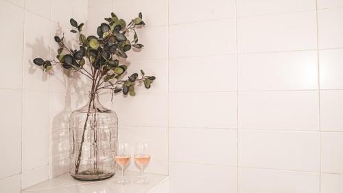 a glass vase with flowers and two glasses of wine at Home Hotel Uppsala in Uppsala