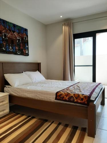 a bedroom with a bed and a large window at Forest View Apartments in Kololi
