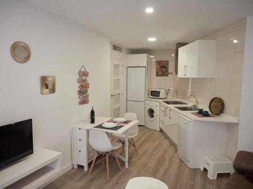 a white kitchen with a table and a counter top at San José Apartamentos Turísticos Miky in Albacete