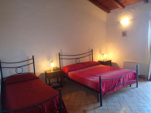 a bedroom with two beds with red sheets and lamps at Patitiri in Santa Teresa di Riva