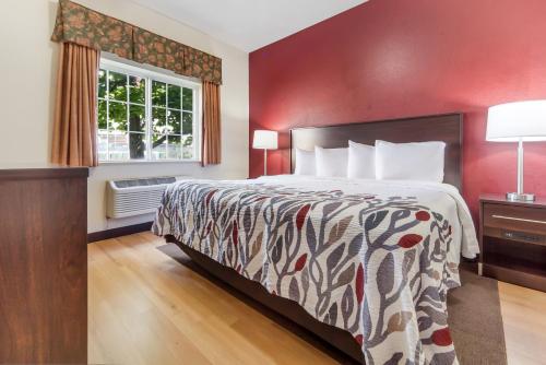 a large bed in a room with a red wall at Red Roof Inn & Suites Omaha - Council Bluffs in Council Bluffs