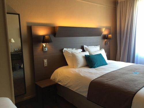 um quarto de hotel com uma cama com uma almofada azul em Moka Hotel em Niort