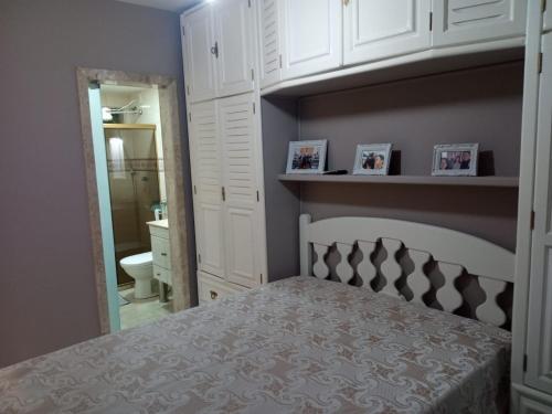Schlafzimmer mit einem Bett, weißen Schränken und einem Badezimmer in der Unterkunft Apartamento CABO FRIO - PRAIA DO FORTE in Cabo Frio