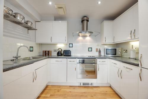 a white kitchen with white cabinets and a sink at Swan Apartments 2A Cosy City Break Staycation in Newcastle upon Tyne