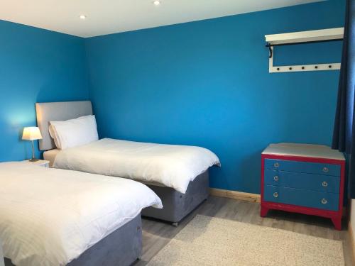 una camera con due letti e una parete blu di Kingfisher Glamping Cabin a Bodmin