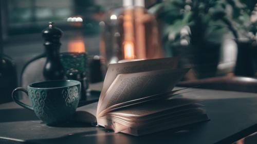 a book and a cup of coffee on a table at Home Hotel Uppsala in Uppsala