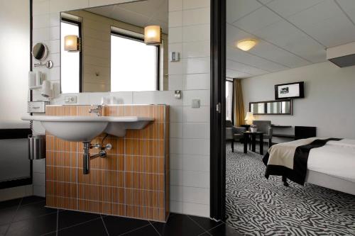 ein Hotelzimmer mit einem Waschbecken und einem Bett in der Unterkunft Hotel De Schout in Denekamp
