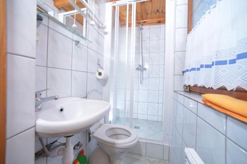 a white bathroom with a sink and a toilet at Domki Pod Wydmami 40m od plaży in Dźwirzyno