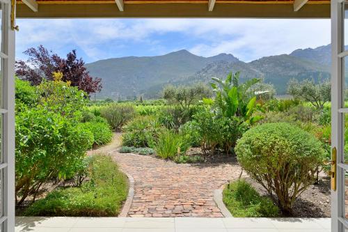 an open door to a garden with mountains in the background at Fransvliet Guest House in Franschhoek