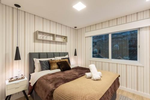 Un dormitorio con una cama grande y una ventana en Vivendas Do Bosque 106 C - Apartamento em Gramado, en Gramado