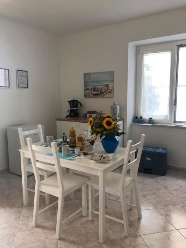 biały stół jadalny z krzesłami i wazon kwiatów w obiekcie B&B MimmoSole w Agropoli