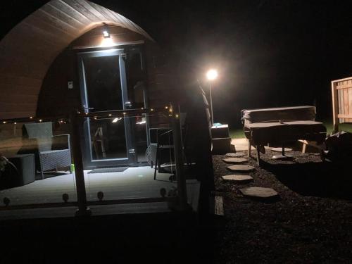 a dark room with a table and a piano at night at Owls Retreat Glamping Pod with Hot tub in Keith