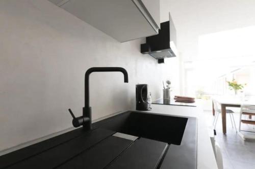 a kitchen with a black sink in a room at Have a nice stay! - Silt14 Sfeervol vakantie appartement in Noordwijk