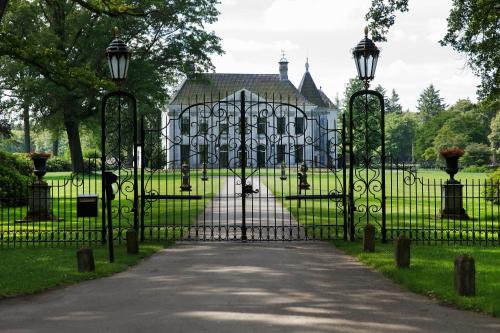 a gate in front of a large building with trees at Hotel De Schout in Denekamp