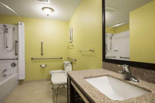 a bathroom with a sink and a toilet and a mirror at Days Inn & Suites by Wyndham Altoona in Altoona