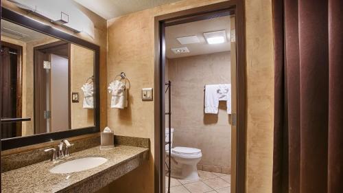 a bathroom with a toilet and a sink and a mirror at Best Western Plus Raton Hotel in Raton