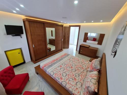 um quarto com uma cama grande e uma cadeira vermelha em Tonny House em La Marsa
