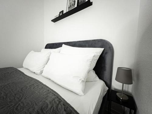 łóżko z białymi poduszkami na górze w obiekcie Wohlfühl-Oase mitten in der Stadt - Garten, Grill, Netflix und Drucker w Lipsku