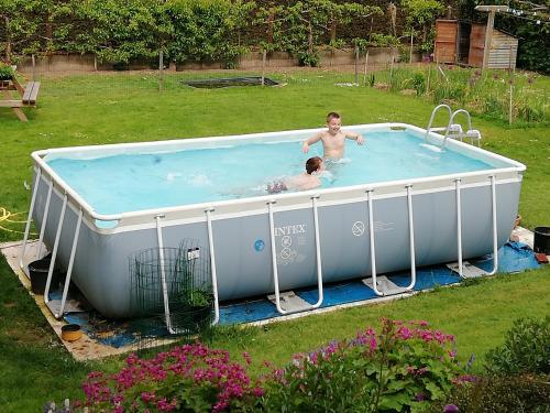un homme et une femme dans un bain à remous dans une cour dans l'établissement Villa Maëlla- Gîte des 2 Chênes & Gîte des Alouettes - Gîte de groupe, à Saint-Michel-la-Forêt