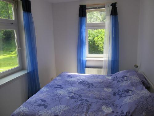 Schlafzimmer mit einem lila Bett und blauen Vorhängen in der Unterkunft Hexenstieg House Lerbach in Osterode