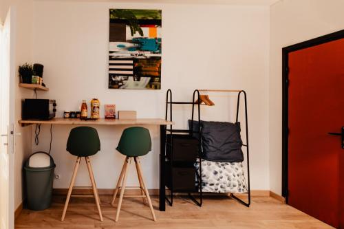Cette chambre comprend un bureau et 2 chaises vertes. dans l'établissement Les Appartements Hyper Centre Valenciennes, à Valenciennes