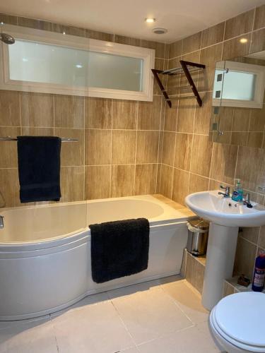 ein Badezimmer mit einer Badewanne, einem Waschbecken und einem WC in der Unterkunft Lovely apartment in beautiful coastal village in Weybourne
