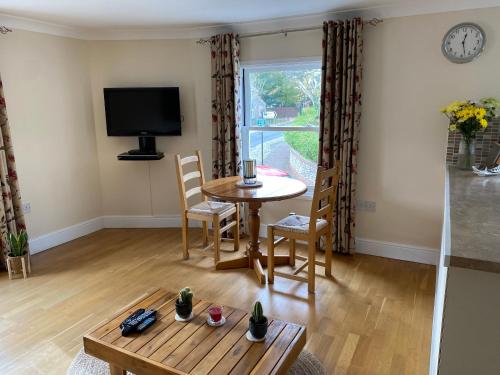 a living room with a table and chairs and a tv at Lovely apartment in beautiful coastal village in Weybourne