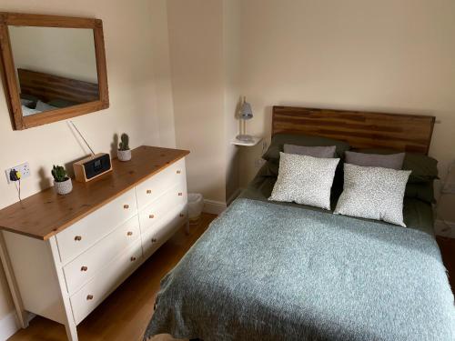 a bedroom with a bed and a dresser and a mirror at Lovely apartment in beautiful coastal village in Weybourne