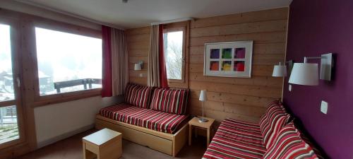 ein Wohnzimmer mit einem Sofa und 2 Fenstern in der Unterkunft Apt With Garden In La Plagne in La Plagne