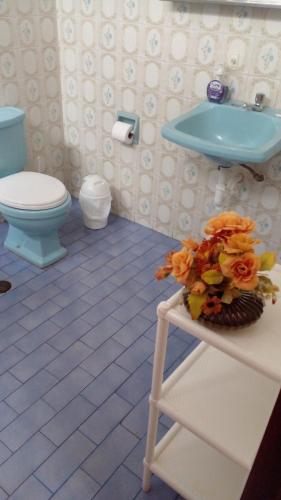 La salle de bains est pourvue d'un lavabo bleu et de toilettes. dans l'établissement Hostal Donde Alberto, à Trujillo