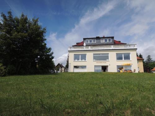 une maison blanche au-dessus d'un champ vert dans l'établissement Ferienwohnung Villa Bella Vista, à Bad Sachsa