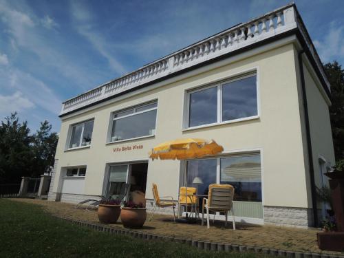 a white house with a table and chairs and an umbrella at Ferienwohnung Villa Bella Vista in Bad Sachsa