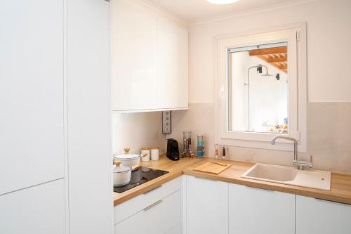 una cucina con armadi bianchi, lavandino e finestra di ETHOS Luxury Home - Seaview Villa with Hot-Tub! a Iraion