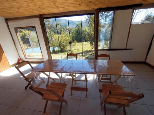 stół i krzesła w pokoju z dużym oknem w obiekcie Chalés Horizonte Vertical w mieście Aiuruoca