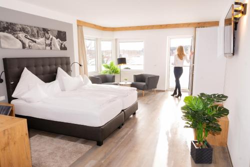 a woman standing in a bedroom with a large bed at Hotel Tanneck in Bad Wörishofen