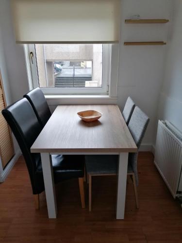 a wooden table with chairs and a bowl on top at Bathgate Handy House in Bathgate