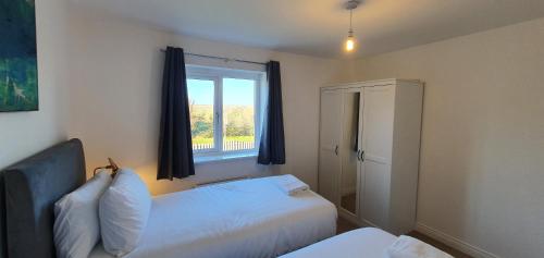 a bedroom with two beds and a window at Garland Modern 4 Bedroom House with Garden & Parking in Kent