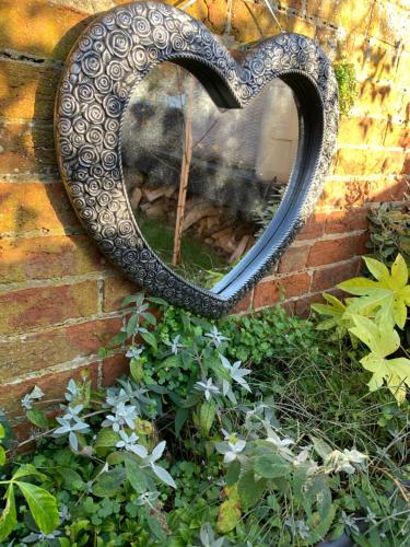 a mirror with a heart on a brick wall at Sandy feet retreat in Exmouth