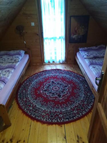 a room with two beds and a rug on the floor at Ośrodek Wczasowy "Wczasy pod gruszą" in Biecz