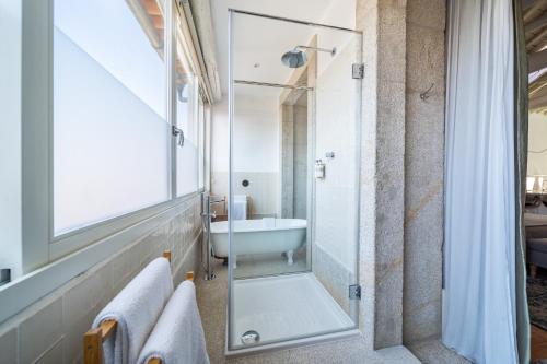 a bathroom with a tub and a glass shower at Casa do Cativo in Porto