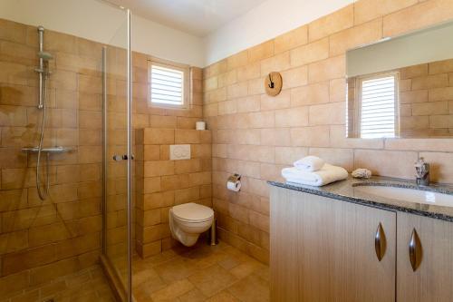 a bathroom with a shower and a toilet and a sink at Kas Sumba in Water Villas in Kralendijk