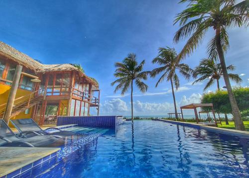 a swimming pool in front of a house with palm trees at Pousada Spa dos Amores in São Miguel do Gostoso